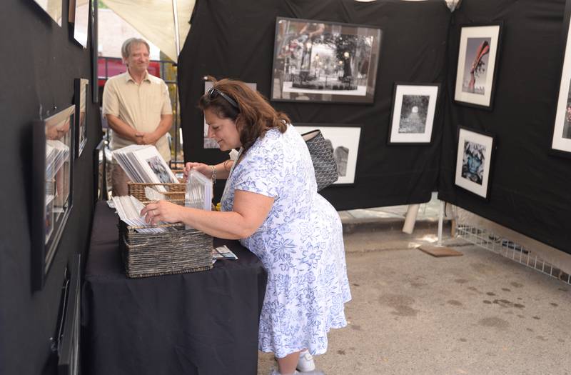 Judy Sardines of Westchester takes a closer look at some if the photography prints made by Brian Horan of Lagrange Park at the LaGrange Craft Fair held Saturday, July 13, 2024.