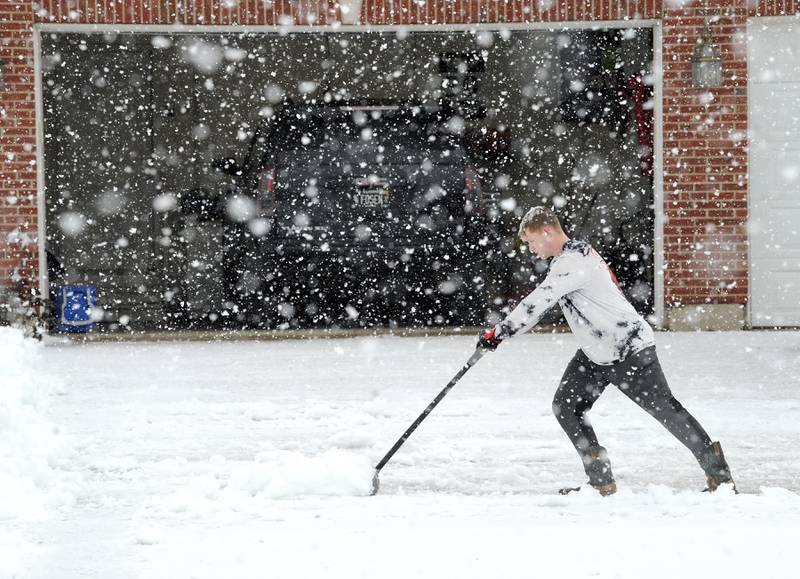 Nick Fosen, 16 pushes the heavy snow off his driveway during a major snowstorm in Yorkville on Tuesday, Jan. 9, 2023.