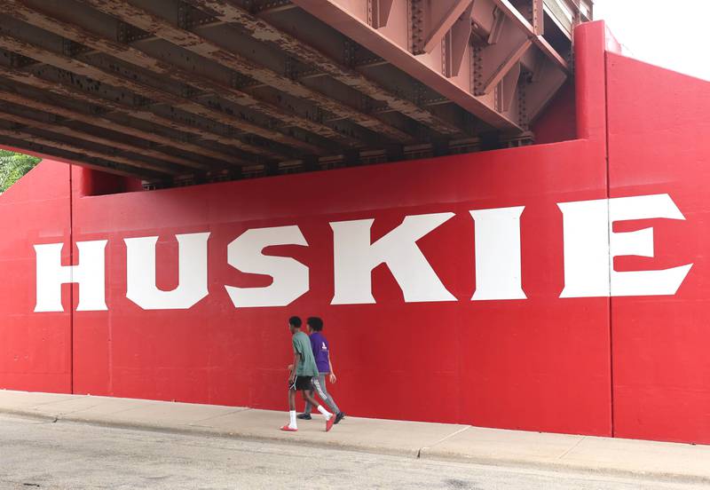 Walkers cross under part of the new Huskie mural Monday, Aug. 7, 2023, on the Annie Glidden Road railroad underpass, just south of Lincoln Highway in DeKalb. The mural was a joint project between the City of Dekalb and Northern Illinois University.