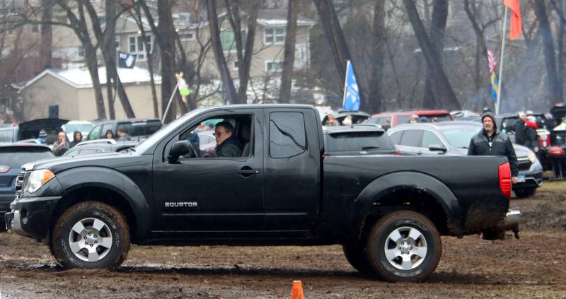 A motorist spins their tires in mud upon attempting to leave the parking area at the 119th Norge Annual Winter Ski Jump Tournament in Fox River Grove Sunday.