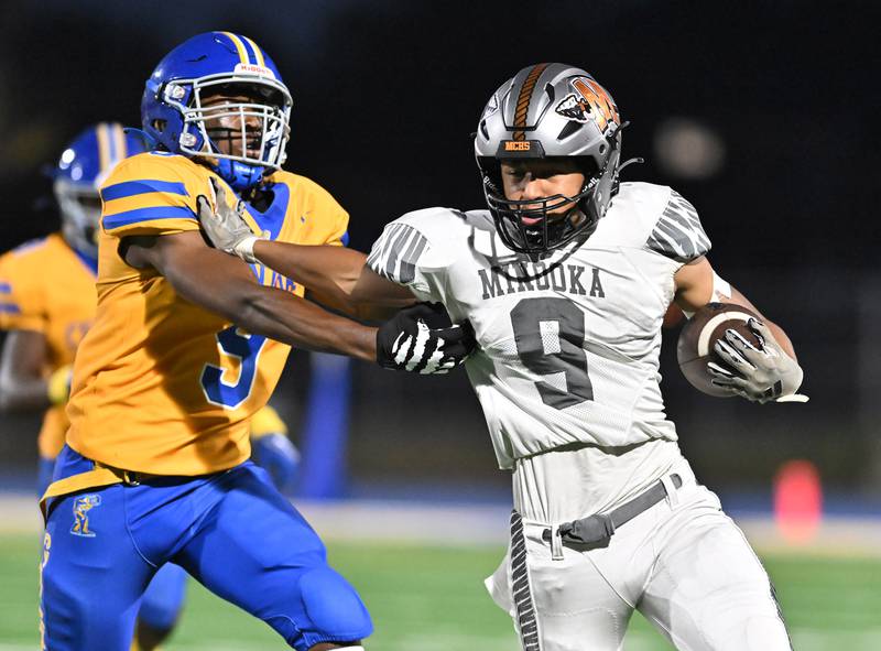 Minooka's Paris Spears (9, in white) stiff-arms Joliet Central's Jotham Word during a nonconference game Friday, Sept. 13, 2024, at Joliet.