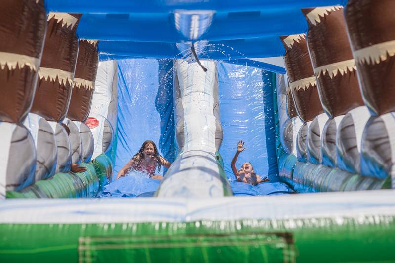 A pair of SPARK campers zip down one of two water slides erected for the day at Ballou Park. The camp is being held June 13, 15 and 17 this week.