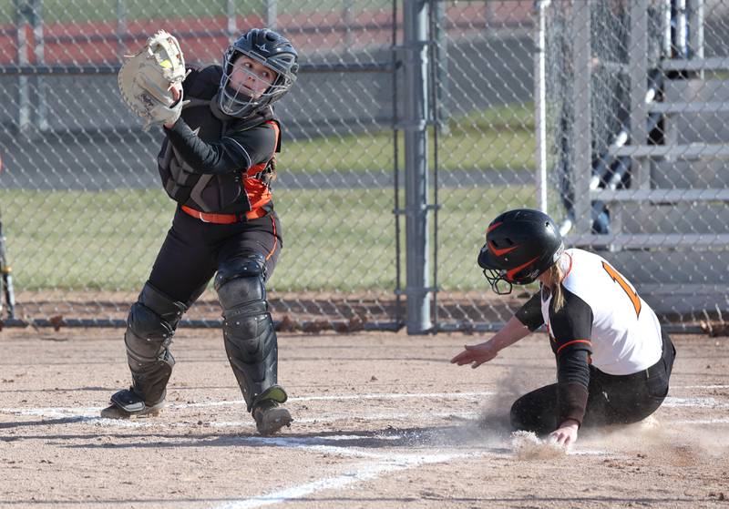 Sandwich's Jillian Ashley slides in ahead of the tag of DeKalb's Madison Hallaron scoring the games first run Tuesday, March 19, 2024, at DeKalb High School.