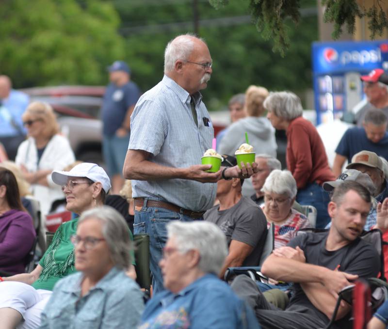 Dale Collins of Mt. Morris carries two sundaes as he weaves his way through the large crowd at the opening night of the  Jamboree music series in downtown Mt. Morris on Friday, June 7, 2024. Brass from the Past was the featured band. The free concert series continues through the summer each Friday night on the campus.