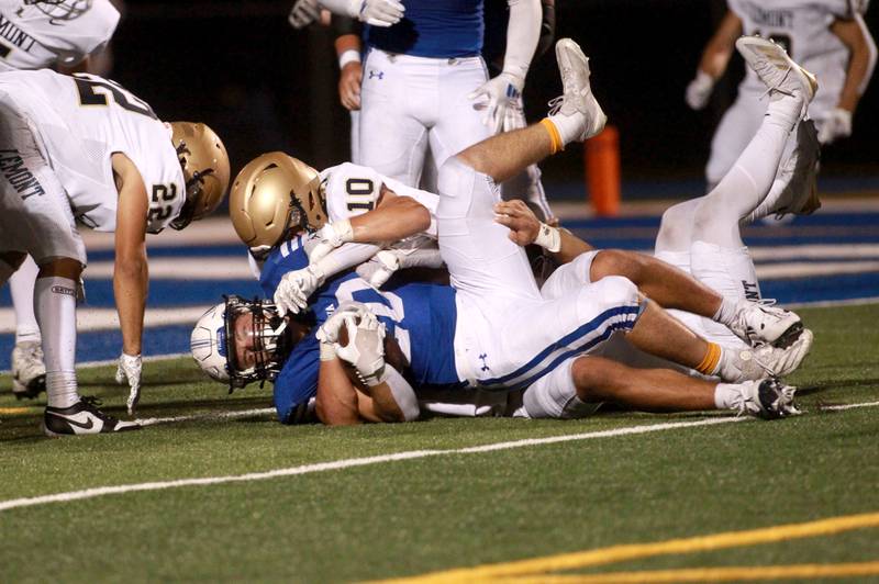 Geneva’s Michael Rumoro lands under a tackle by Lemont’s Dylan Wilms during a game Friday, Sept. 6, 2024 at Geneva.