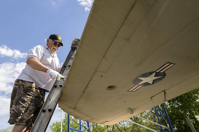 Bob Balayti works on the top of the wing of the Thunderchief jet Wednesday, May 8, 2024. With lots of peeling paint on this section of the plane, a fresh coat was much needed. Balayti is excited about the project, “how many people can say they painted a jet,” he said.