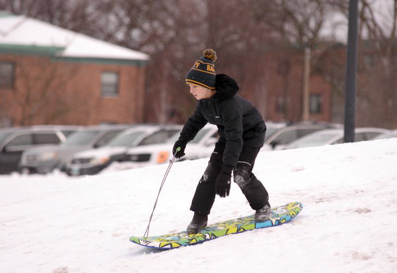 Owen Cisek of Lagrange Park snow boards down the Memorial Park hill in Lagrange Park Saturday, Jan 13, 2024.