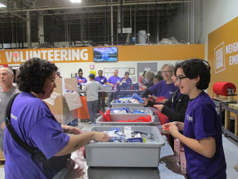 Alex Demos (right) joins his mother Sarah Demos, a Northwestern Medicine employee who lives in Palos Park, on Saturday as they wrap toothbrushes and toothpaste donated by Procter & Gamble, at the Northern Illinois Food Bank South Suburban Center in Joliet. Feb. 24, 2024.