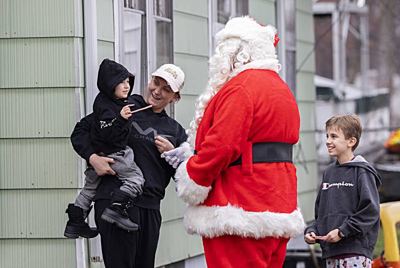 Dylan Jablonski, 3, with mom Teresa and brother Daniel Galkowski, 14, accepts a candy cane from Santa Friday, Dec. 22, 2023 during a delivery for RFPD’s Operation Santa Claus.