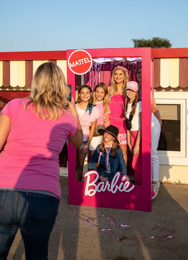 Attendees pose with Barbie, Emma Heinlein, during the "Barbie" movie premiere at the McHenry Outdoor Theater on Friday,  July 21, 2023.