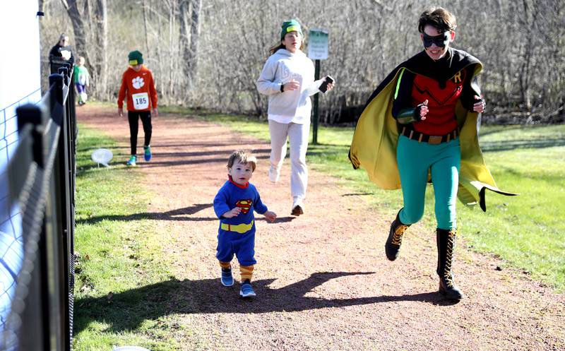 Ethan Beale, 16 months, of Naperville crosses the finish line during the Wheaton Park District’s Superhero 3K Fun Run at the Sensory Garden Playground in Lisle on Saturday, April 6, 2024.