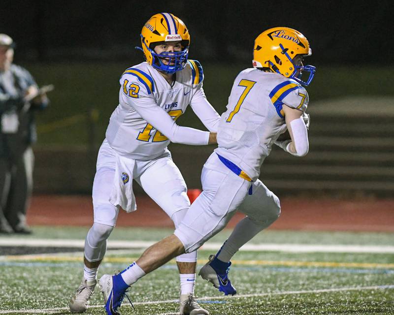 Lyons Township's Dom Pisciotti (12) hands the ball off to teammate Danny Carroll (7) during the game on Friday Oct. 18, 2024, while traveling to take on York High School in Elmhurst.