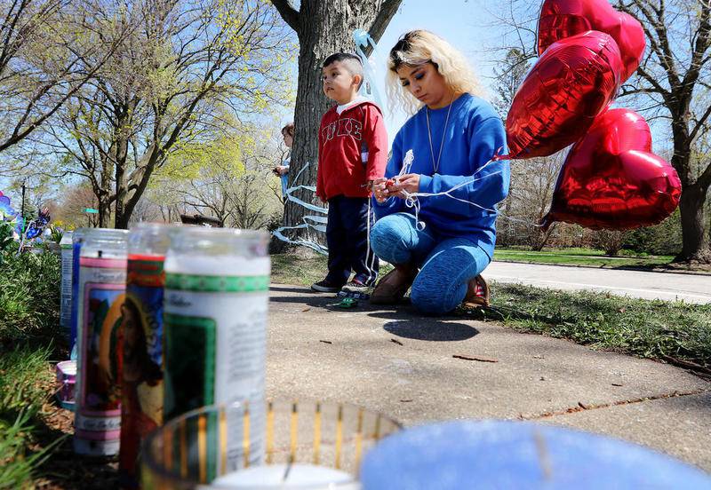 Jennifer Rodriguez of Crystal Lake ties three heart-shaped balloons to a toy car as she and cousin Brian Pastor, 4, pay their respects to Andrew (AJ) Freund at 94 Dole Ave on Friday, April 26, 2019 in Crystal Lake.