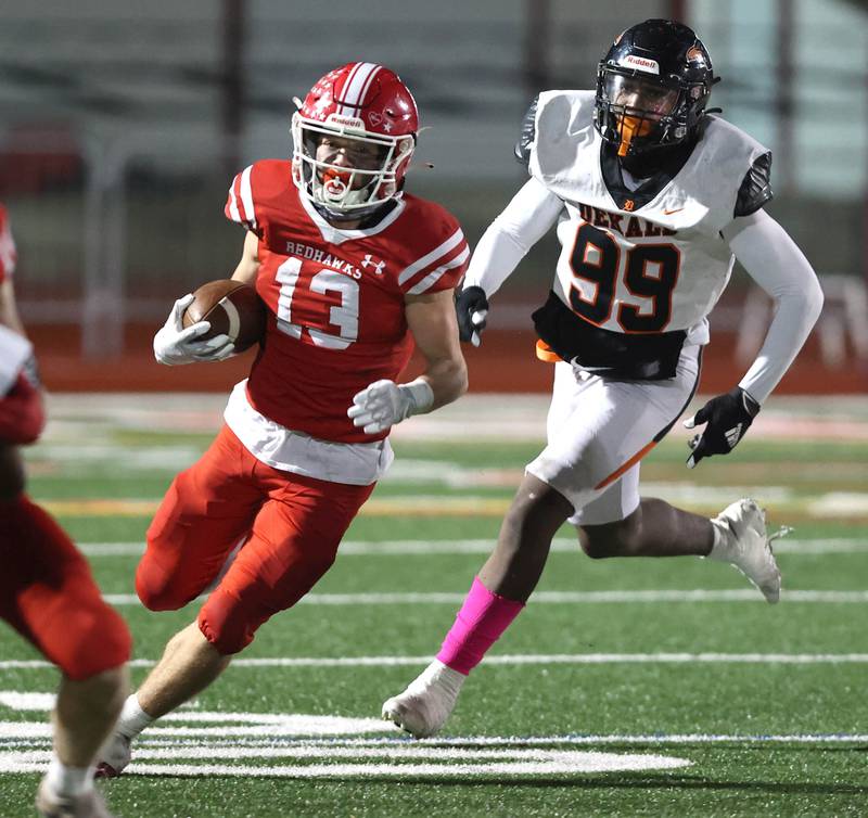 Naperville Central's Aiden Clark runs by DeKalb’s Pierre Cathina during their game Friday, Oct. 6, 2023, at Naperville Central High School.