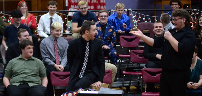 Oregon High School Choir Director Zach Hall sits on the Christmas present he received as Brady Davis tells him it is a new chair. The choir presented Hall with the gift during the OHS Christmas Concert held Sunday, Dec. 17, 2023 at Oregon High School.