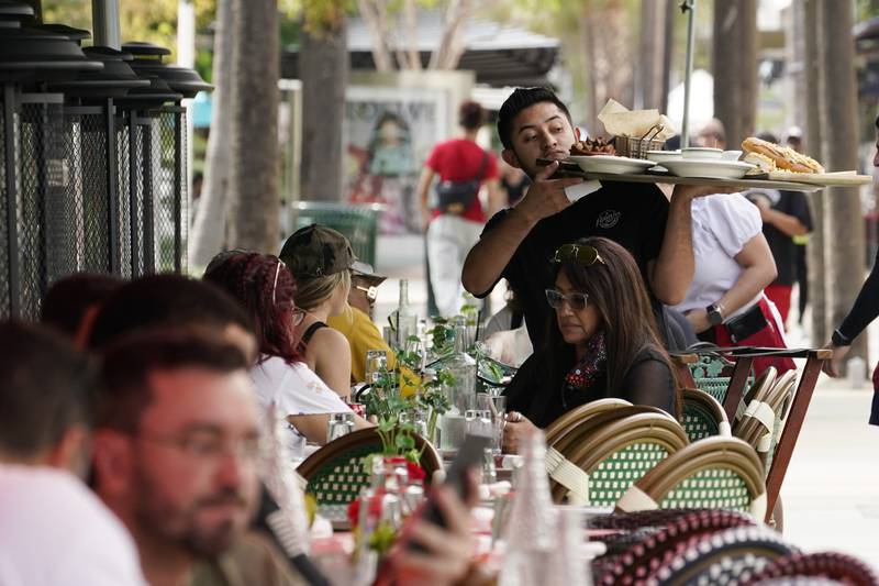 FILE - A waiter delivers food to patrons at a restaurant, Jan. 21, 2022, in Miami Beach, Fla. (AP Photo/Marta Lavandier, File)