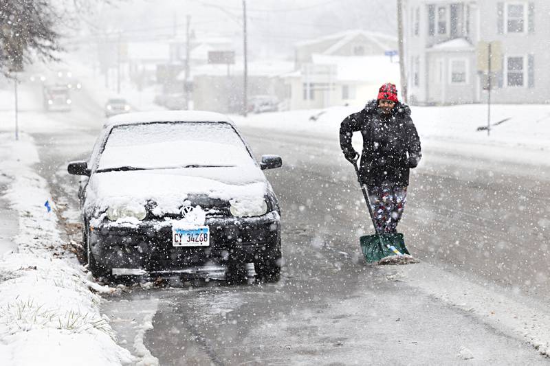 Puchi Molina clears the area around her car Tuesday, Jan. 9, 2024 in Sterling as snow continues to fall.