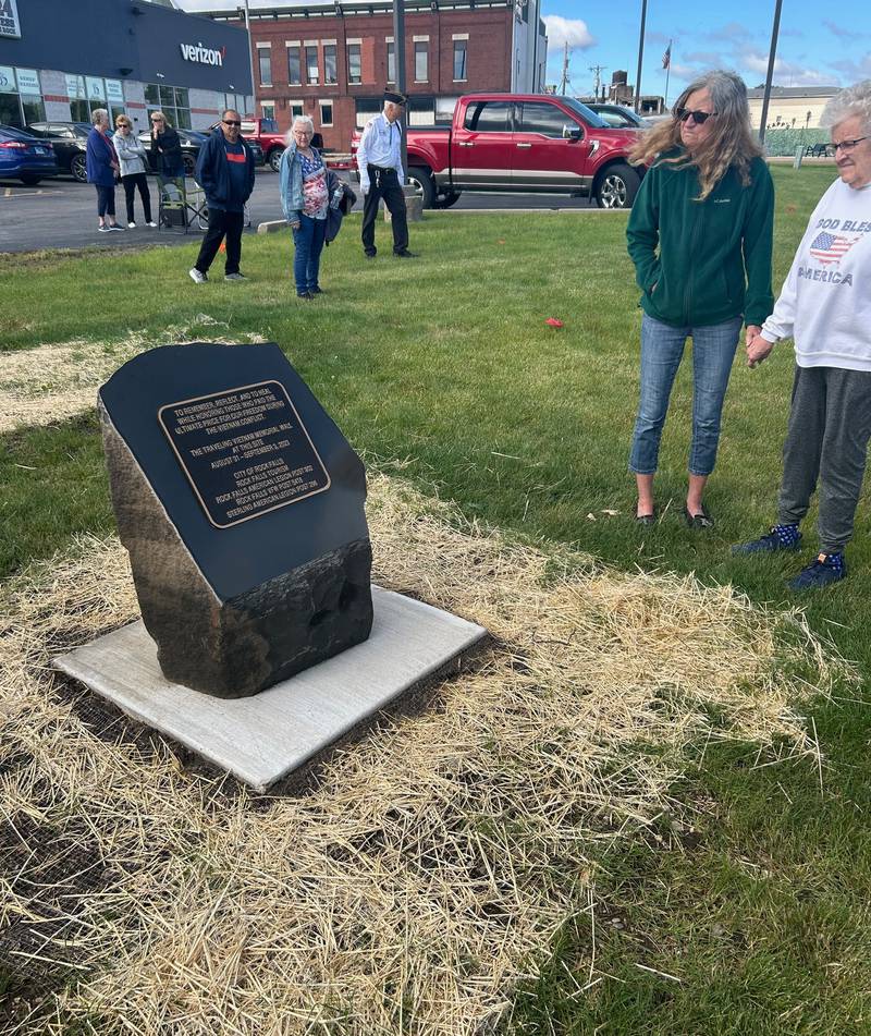 Visitors view a plaque commemorating the Traveling Vietnam Memorial Wall display Monday in the RB&W District in Rock Falls.