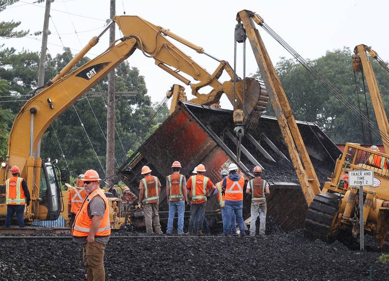 Workers watch as cranes and a loader upright a tipped over coal car after a BNSF Railway train traveling east derailed Wednesday, July 10, 2024, near Route 34 on the west side of Somonauk.