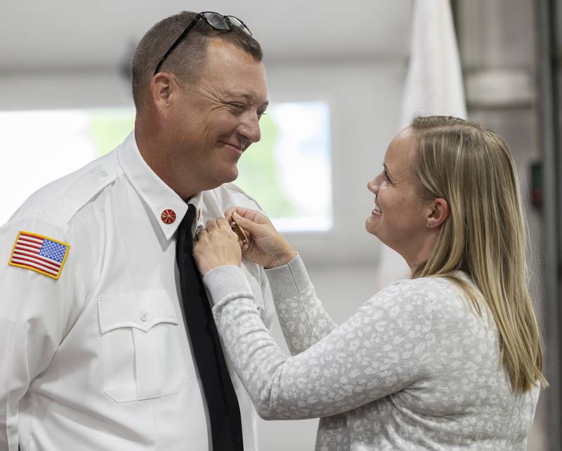 Jennifer Storey pins husband Derrick’s new badge on him Tuesday, May 14, 2024 after being sworn in as new assistant fire chief of Dixon Rural.