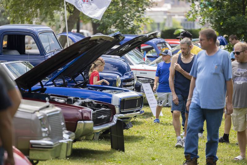 Car lovers walk among the shiny chrome and sleek lines of classic and modern autos Monday, July 3, 2023 at John Dixon park for the annual Petunia Fest car show.