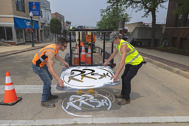Matt Kerchner (left) and Collin Brady remove the stencil  Wednesday, June 28, 2023 after marking the path for the Regan Run 5K on Hennepin Avenue in Dixon.