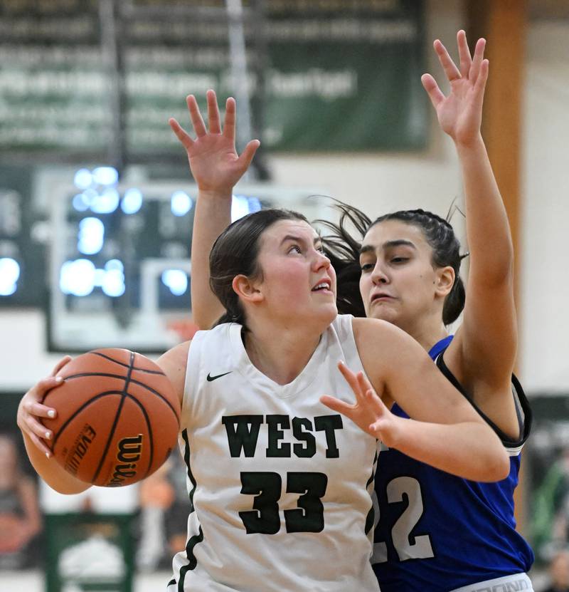 Glenbard West’s Makenna Yeager, left, makes a move to the basket against Geneva’s Leah Palmer during the Glenbard West Class 4A girls basketball regional final on Thursday, Feb. 15, 2024 in Glen Ellyn.