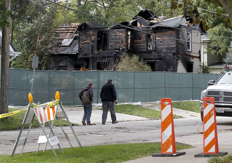 People walk past the remains of homes in the 300 block of Lincoln Avenue on Tuesday, October 10, 2023, after an explosion following a gas leak in the area leveled one home as caused several fires.