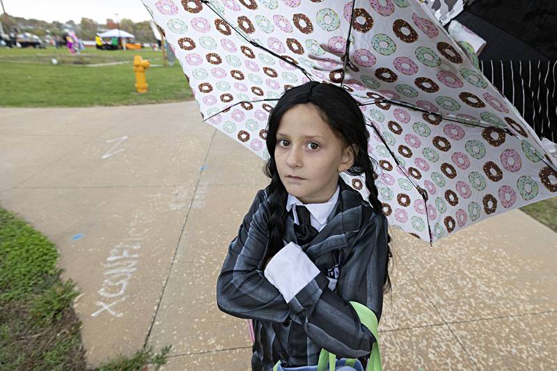 Playing into the court character “Wednesday,” Corinna Pageloff, 7, of Rock Falls stays dry while attending the Biz Boo trick-or-treat event in Rock Falls Friday, Oct. 27, 2023.