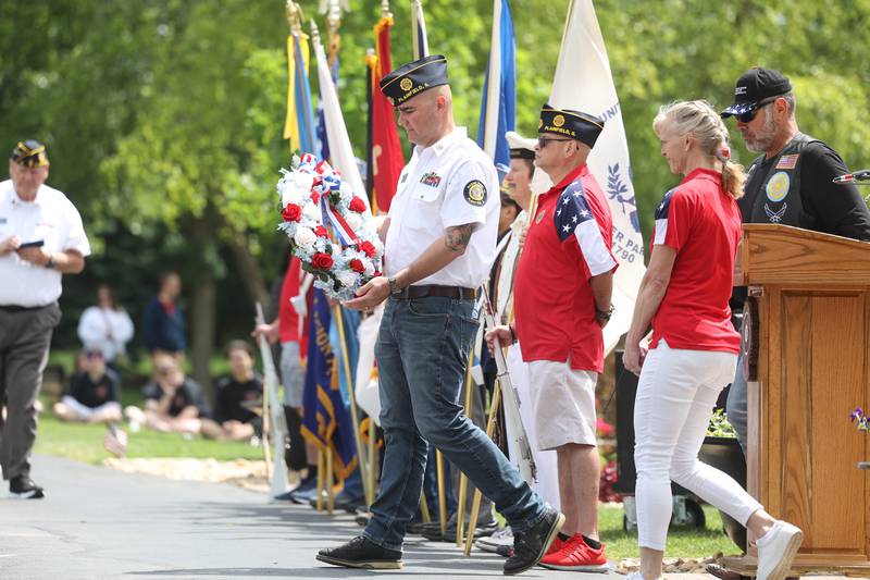 A member of the American Legion Post 13 carries a wreath to place at one of the memorials at Plainfield’s Memorial Day and Ceremony event on Monday, May 27, 2024.