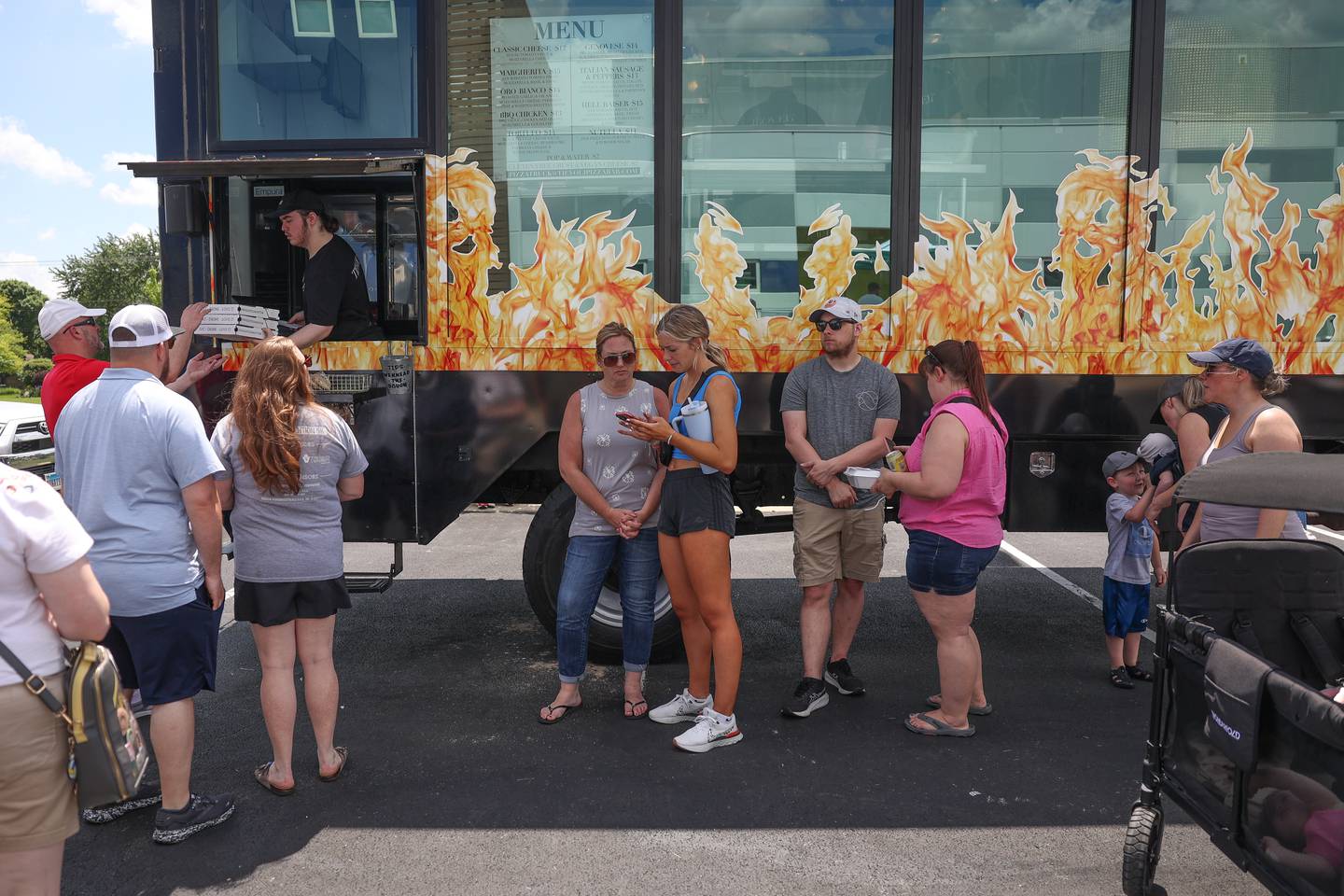 People wait to get pizza from Tievoli, work fire pizza truck, at the World of Food Trucks on Saturday, May 18, 2024 at Renwick Community Park in Plainfield