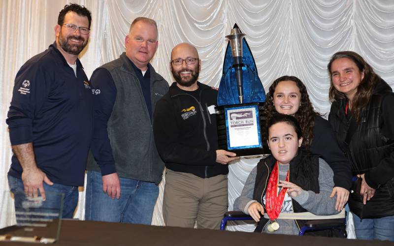 Geneva Police Officer Chuck received the Flame of Hope Award Feb. 2, 2024, during the Illinois Torch Run for Special Olympics kickoff conference in Bloomington. Assistant Torch Run Director Officer Dan McIntyre (left) of the Woodridge Police Department, Torch Run Director Sgt. Bill Devine, Parisi, Parisi's oldest daughter, Special Olympics athlete Sami, back row his younger daughter, Amanda, a special education teacher at Geneva Middle School South, and  his wife, Eva.