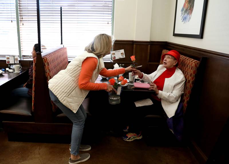 Random Acts Matter volunteer Sharon LeGare (left) hands an orange rose to Bev Paonessa at the Brunch Cafe in St. Charles as part of Random Acts of Kindness Week on Wednesday, Feb. 14, 2024.