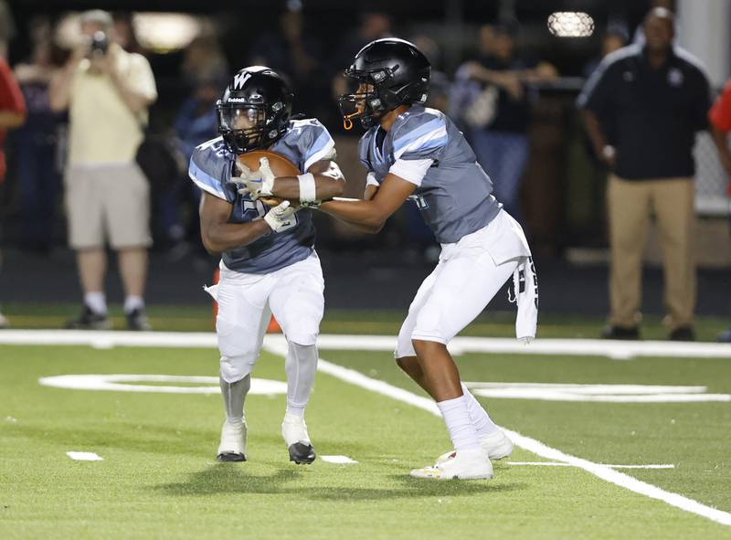 Willowbrook's Jovon Boyd (30) takes a handoff from Jabonise Reed (11) during the varsity football game between Glenbard East and Willowbrook high schools on Friday, Sep. 30, 2024 in Villa Park.