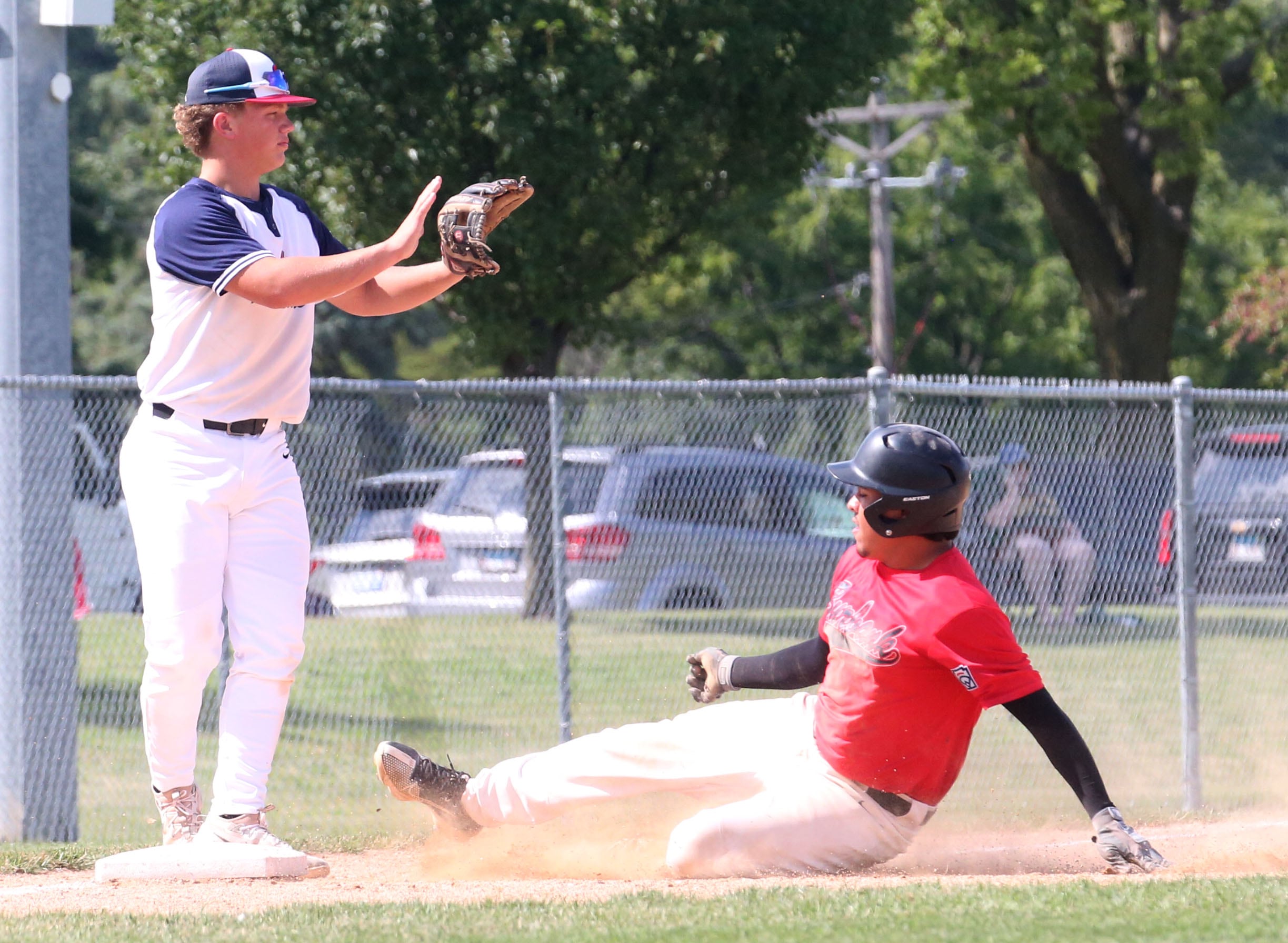 Burbank's Orlando Vazquez slides in safely to third base as Michigan's Breckton Meeuwsen halts the throw during the Central Regional Baseball Tournament championship on Thursday, July 18, 2024 at J.A. Happ Field in Washington Park in Peru.