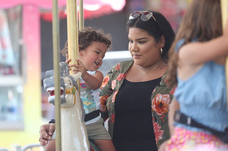 Lily Garcia stands by her daughter Kaiden as she rides the merry-go-round at Plainfield Fest on Saturday June 29, 2024.