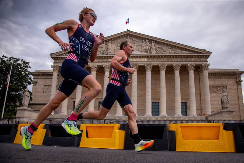 Owens Cravens, left, and his guide Ben Hoffman, run past the French National Assembly in Paris, where Cravens competed in the triathlon at the 2024 Paralympics.