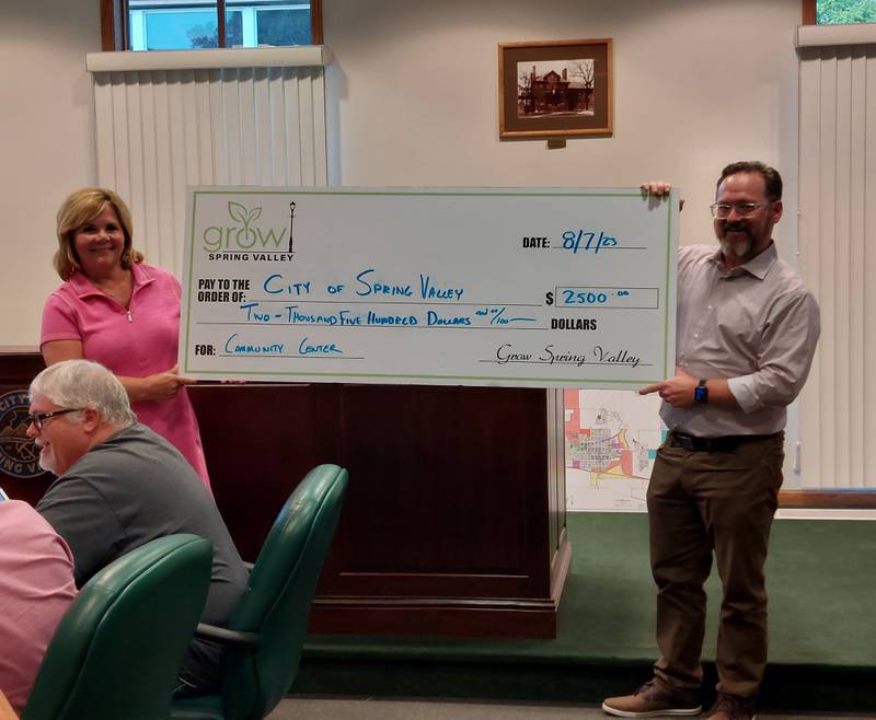 Spring Valley Mayor Melanie Malooley-Thompson (left) shows off a ceremonial check for $2,500 with GROW Spring Valley President JC Heerdt. GROW Spring Valley donated $2,500 of a $10,000 grant to the city's downtown community center project.