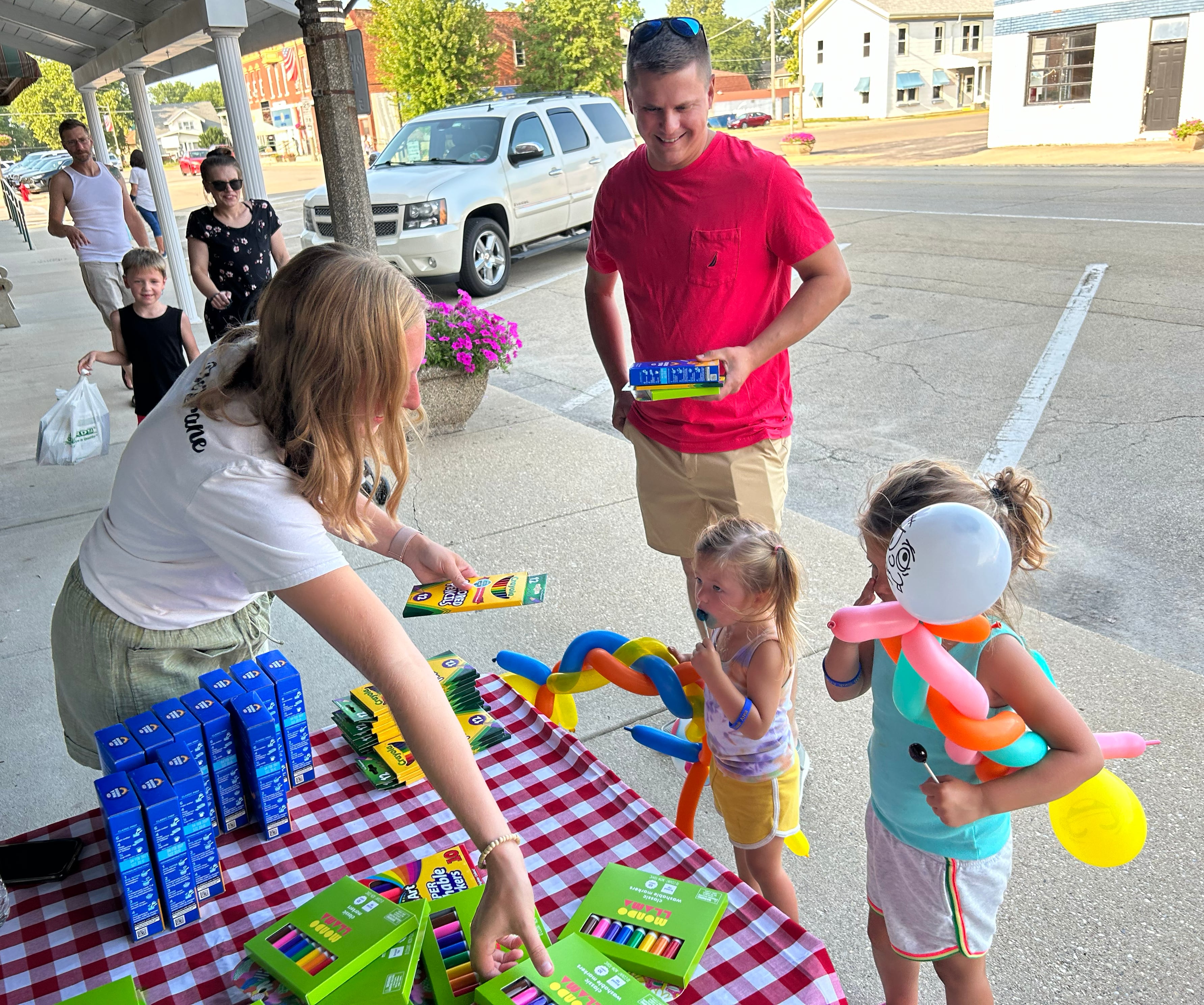 Anna and Leah Larson, 4 and 2, of Prophetstown, pick up school supplies at one of the booths as their dad, Luke watches, during Prophetstown's Fourth Friday on Friday, July 26, 2024.