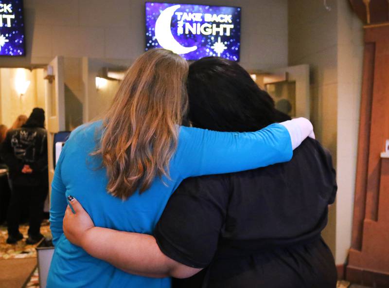 Attendees embrace as they listen to speakers Tuesday, April 2, 2024, during Take Back the Night at the Egyptian Theatre in DeKalb. The event, hosted by Safe Passage, is in honor of Sexual Assault Awareness Month and featured speakers and a march.