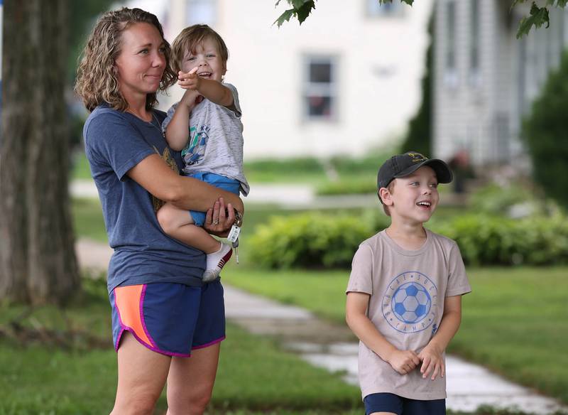 Lyra Liechty and her boys William, 6, and Seth, 2, from Somonauk, watch as a coal car of a BNSF Railway train is uprighted after it derailed Wednesday, July 10, 2024, near Route 34 on the west side of Somonauk.