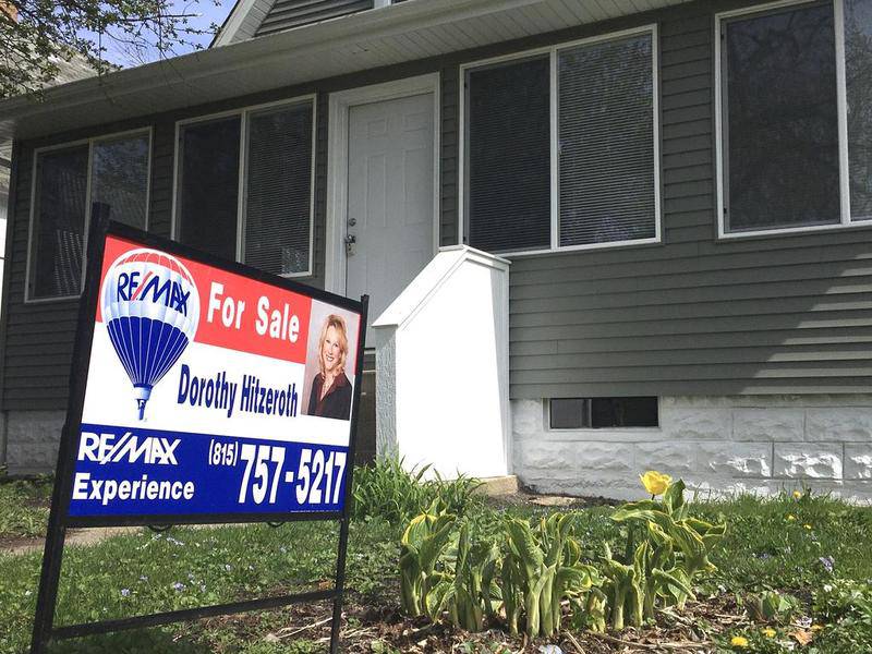 A for sale sign hangs in front of a house on Grove Street in DeKalb.