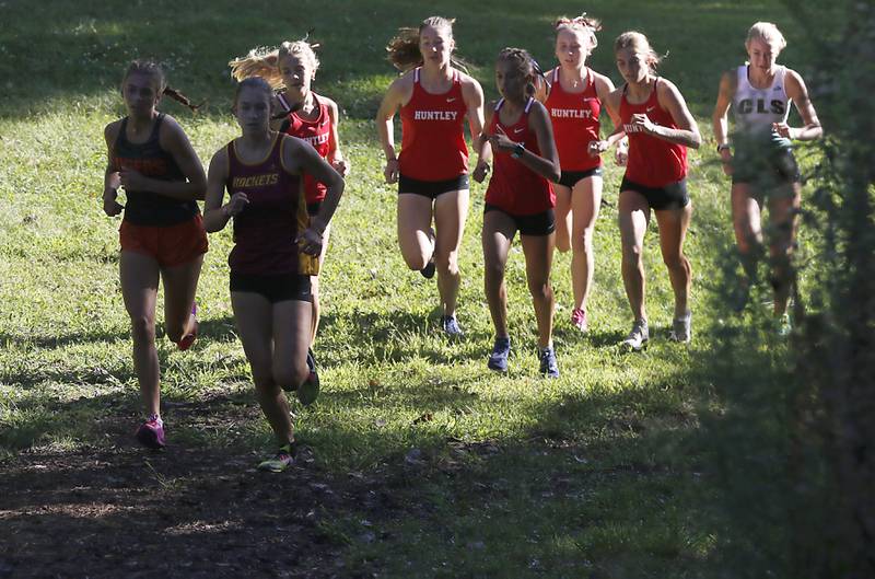 Competitors in the girls race run through the sun and shadows during the McHenry County Cross Country Invite on Saturday, August 31, 2024, at McHenry Township Park in Johnsburg.