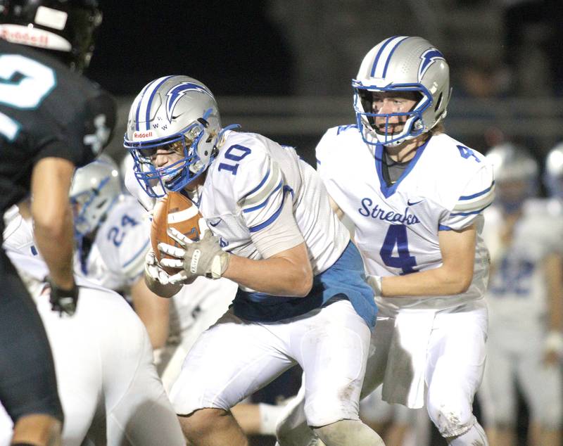 Woodstock’s Caden Thompson, right, hands off to Landen Stoltz in varsity football at Woodstock North Friday night.