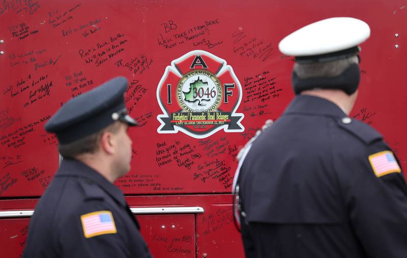 Firefighters look at messages written on a vintage fire truck for firefighter/paramedic Bradley Belanger Saturday, Jan. 6, 2024, during the visitation for Belanger at the Sycamore Park District Community Center. Belanger, 45, who worked with the Sycamore Fire Department for more than two decades, died Friday, Dec. 22, after a yearlong battle with cancer.