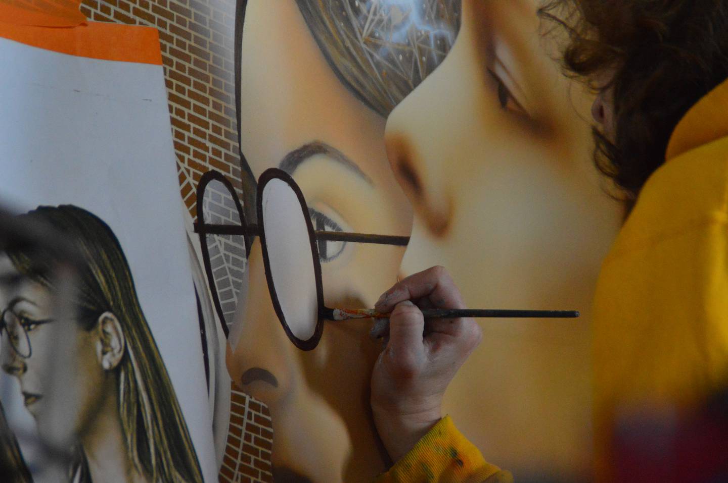 Artist Emily Maze polishes a pair of spectacles on a section of Illinois Valley Community College’s 100th Anniversary mural. Conceived and created by Westclox Studios artist Ray Paseka and his assistants this spring, the mural was installed on campus in May and will be dedicated in a ceremony June 25.
