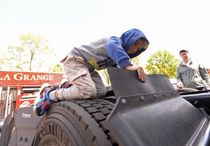 Mateo Gonzalez of LaGrange Highlands climbs the back tires of a semi truck  during the La Grange Park District's Touch A Truck event held at Sedgwick Park Saturday May 11, 2024.