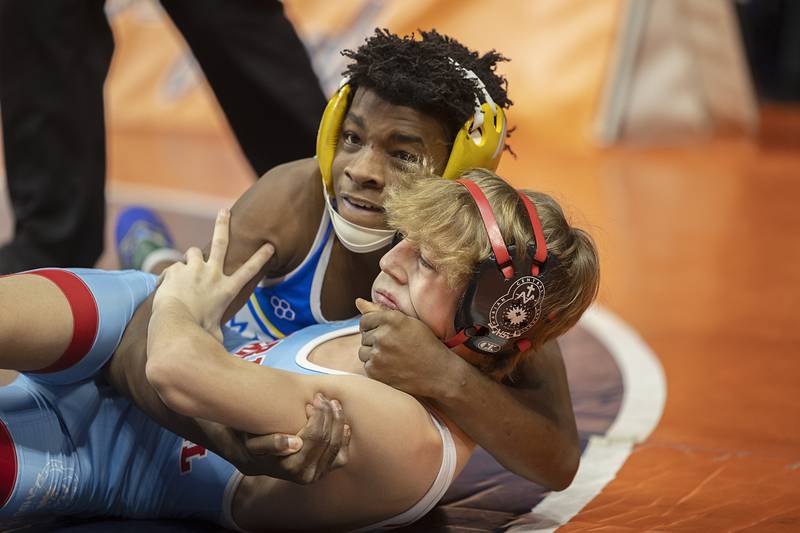 Jeremiah Lawrence of DeLasalle (top) works against Marian Central’s Austin Hagevold in the 106 pound 1A third place match Saturday, Feb. 17, 2024 at the IHSA state wrestling finals at the State Farm Center in Champaign.