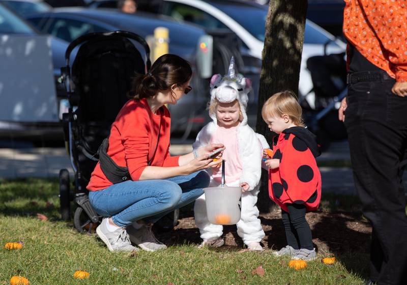 Anna Blyth, right,  Molly Peterson (2), middle, and Maddie Larson (1) pick pumpkins during the pumpkin patch portion of Boo Bash at the Glen Ellyn Park District on Saturday, Oct. 22, 2022.