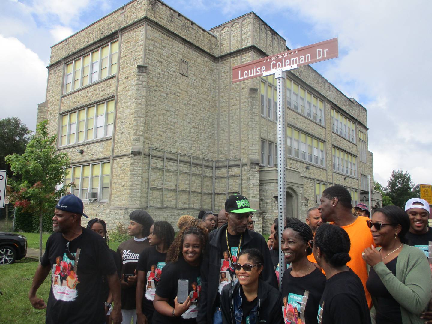 Friends and family gather for photos by the sign marking the new honorary Louise Coleman Drive in Joliet after an unveiling ceremony on Saturday, Aug. 17, 2024.